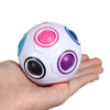 A white fidget cube with colorful, round, translucent colored pieces is held in a person's hand.