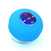 A bright blue compact waterproof Bluetooth speaker with a control panel and suction cup mount.