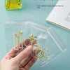 يد تمسك بصندوق تخزين مجوهرات بلاستيكي شفاف يحتوي على عقود وأقراط ذهبية اللون