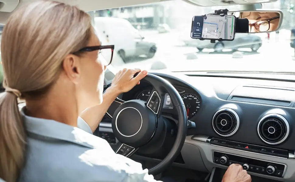 En kvinne kjører bil med en telefon montert på frontruten med et 360-graders roterbart feste.