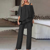En kvinne modellerer et svart todelt sett med off-shoulder topp og vide bukser.
