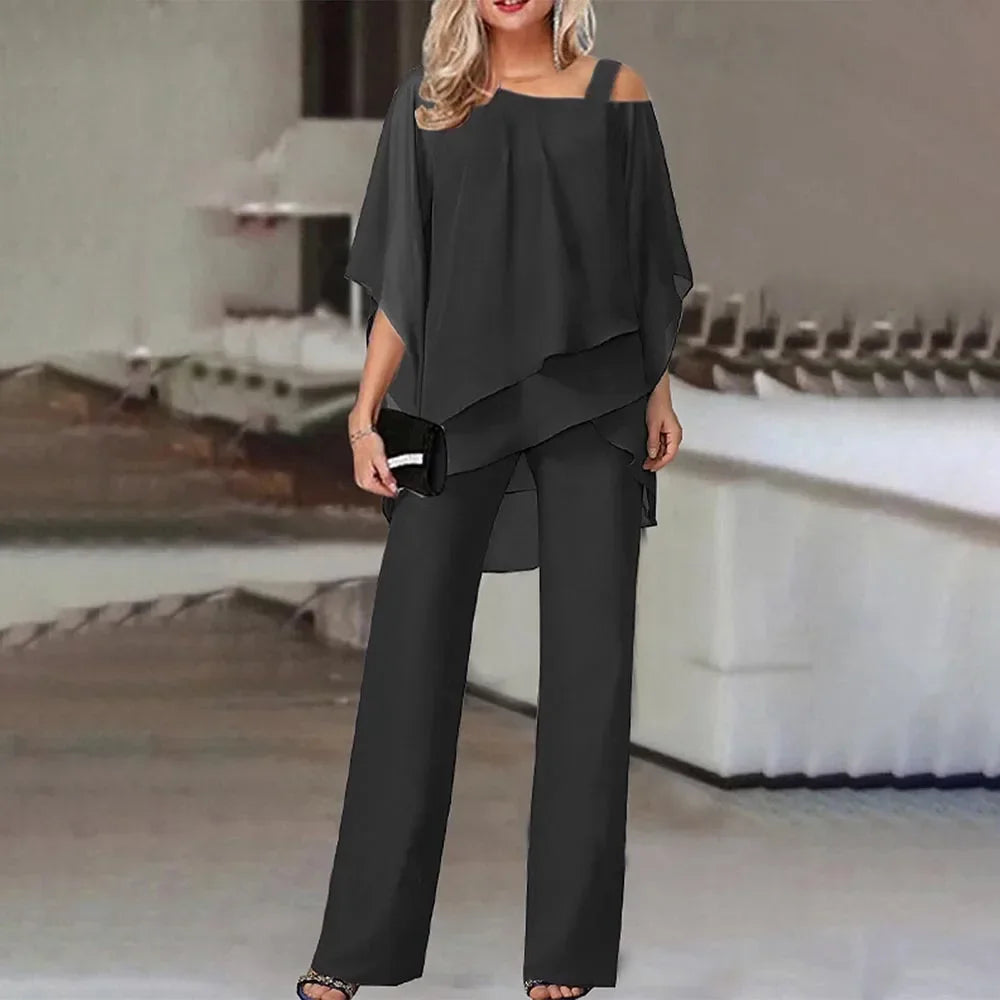 En kvinne modellerer et svart todelt sett med off-shoulder topp og vide bukser.