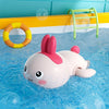 A pink duck bath toy is floating in blue water with a yellow ring and a green rack visible in the background.
