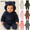 A baby wearing a dark blue fleece hooded romper with a zipper, shown in a studio setting.