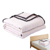 A stack of light pink breathable cooling throw blankets folded neatly on a wooden surface.