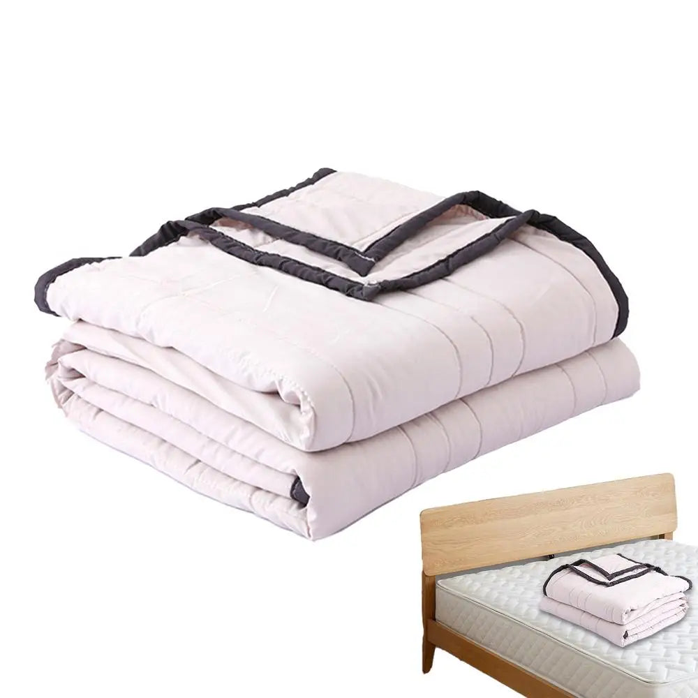 A stack of light pink breathable cooling throw blankets folded neatly on a wooden surface.