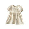 A light beige girls summer dress with white floral embroidery and delicate lace trim.