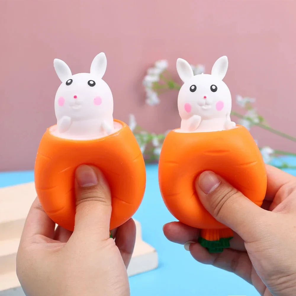 Manos sostienen un juguete antiestrés naranja con forma de zanahoria y un conejo blanco encima.