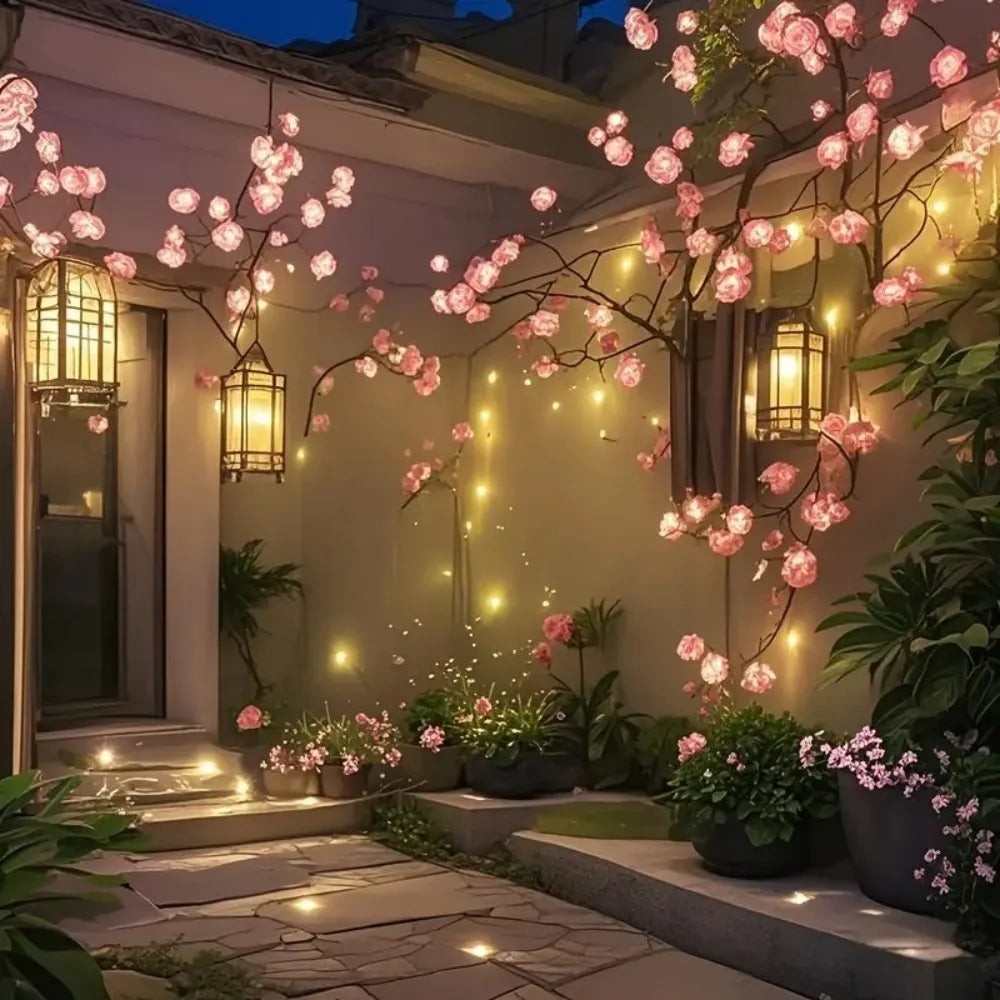 Ett dekorativt träd med rosa körsbärsblommor och varma LED-lampor lyser upp en uteplats.