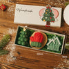 Ein Geschenkset mit handgefertigtem Weihnachtsbaumschmuck und grüner Strickkerze in Holzkiste.