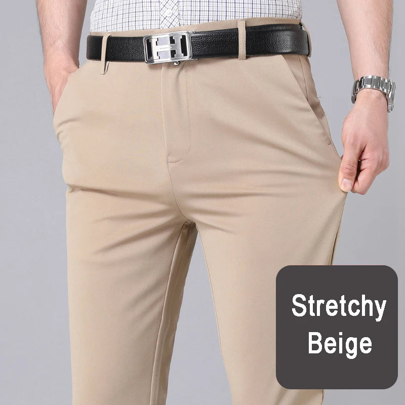 A man wearing beige stretch trousers and a black belt, standing in a casual office setting.