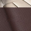 Close-up view of a tan leather seat with a black repair patch and a section of dark brown perforated leather.