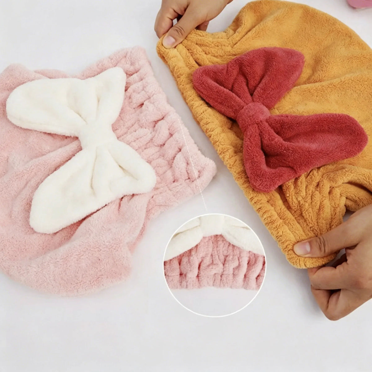 Dos gorros de secado de pelo esponjosos, uno rosa y otro amarillo, con lazos, mostrando el producto.