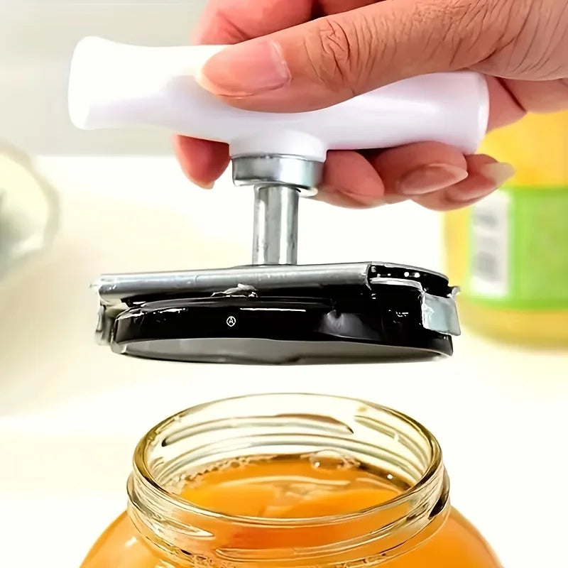 A hand holds a white and silver adjustable jar and bottle opener tool above an orange liquid in a glass jar.