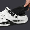 A hand is placing a black and white EVA slip-on sandal onto a dark gray surface.