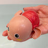 A hand is holding a pink duck bath toy with a red shell and a yellow beak.