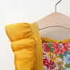 A yellow dress with a floral print bodice and matching yellow trim is displayed on a wooden hanger.