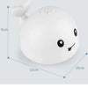 A white musical whale bath toy with a light-up water spray is shown from above.