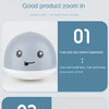 A white, spherical bath toy with a cute cartoon face and light-up features is shown in a close-up view.