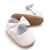 White soft non-slip baby first walker shoes with a bow detail and tan sole.