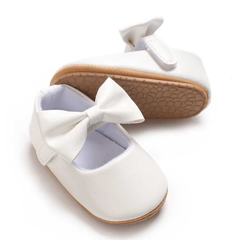 White soft non-slip baby first walker shoes with a bow detail and tan sole.