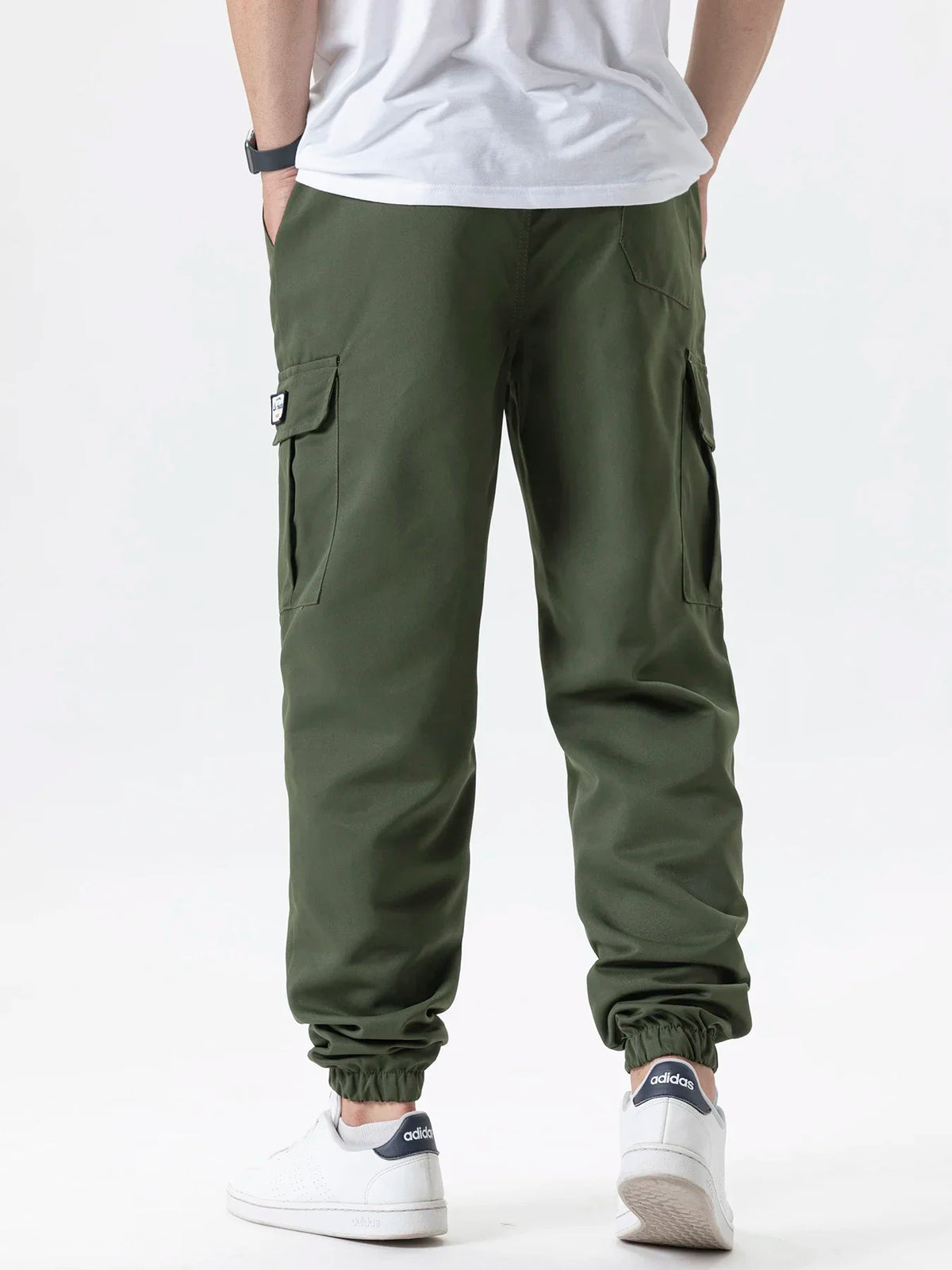 Men's olive green cargo joggers with pockets and white Adidas sneakers