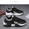 Paire de sneakers à plateforme noires et grises, semelles blanches, sur fond gris.