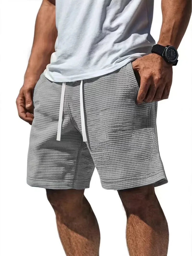 Shorts casual gris de textura waffle para hombre con cordón, usados por una persona.
