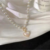 A delicate necklace featuring a heart-shaped pendant made of simulated pearl and strung on a strand of small pearls.
