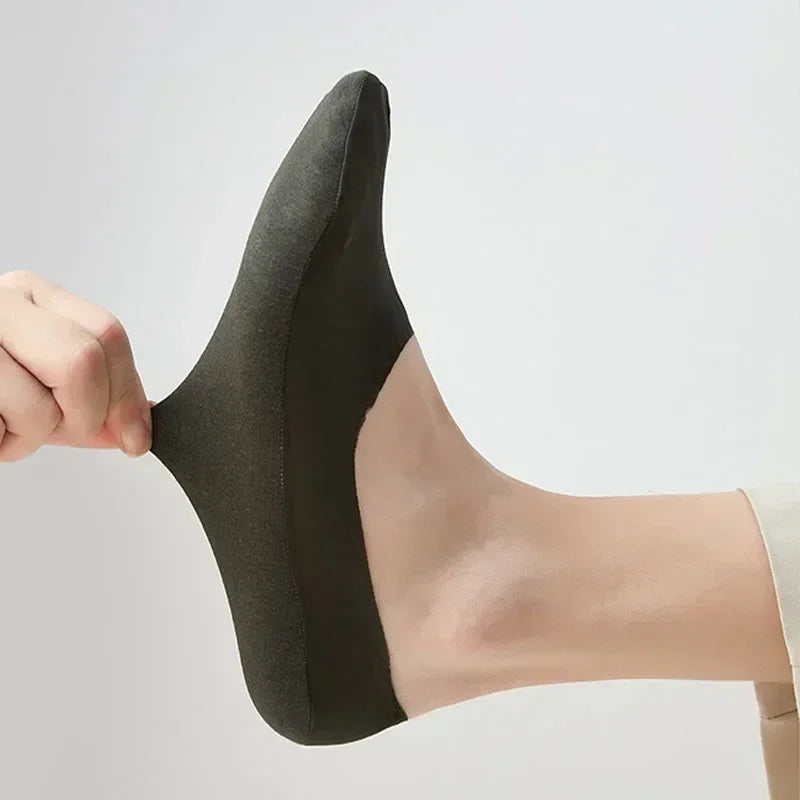 A close-up of a black men's no-show sock with silicone grip being held on a foot.