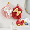 Juego de gorros de microfibra rosas y rojos con lazos blancos y amarillos colgados en una pared de azulejos blancos.