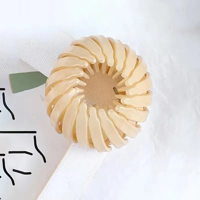 Lyst beige fuglerede-hårspenne formet som en spiral til hestehaler.