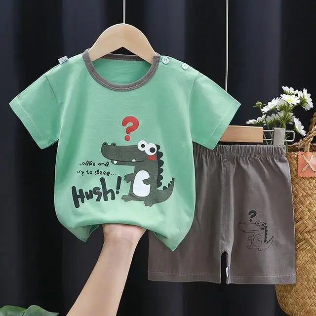 A green dinosaur print kids t-shirt and shorts set displayed on a hanger.