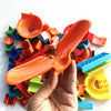 A hand holds an orange marble run building block with a track and funnel component.