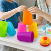 Two hands are stacking bright colored plastic cups on a table for a children's game.