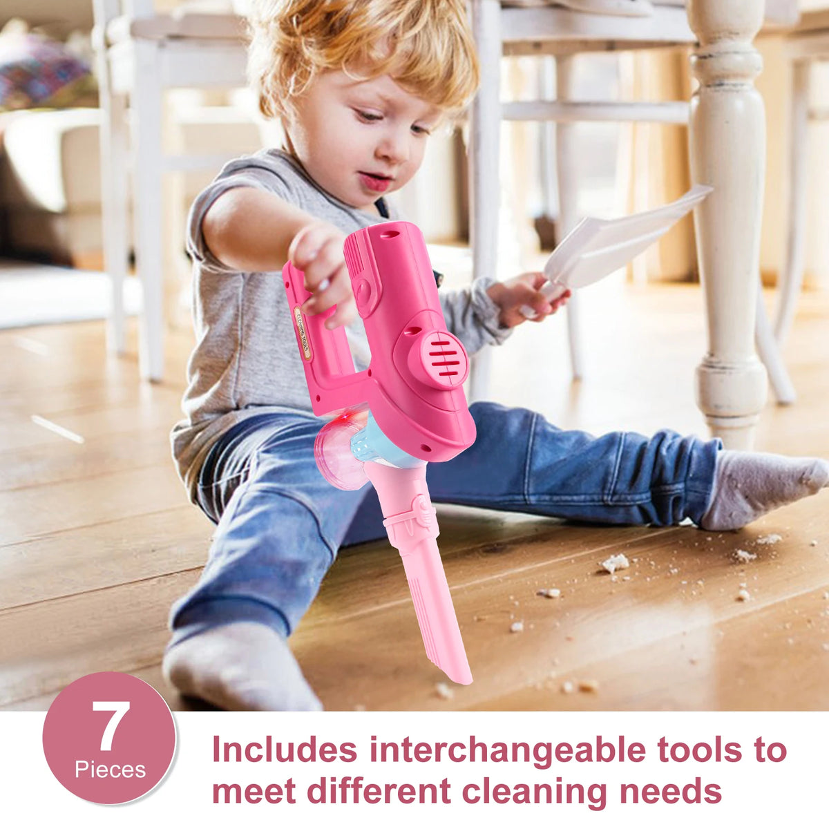 A young child is using a pink toy vacuum cleaner with interchangeable tools on a wooden floor.