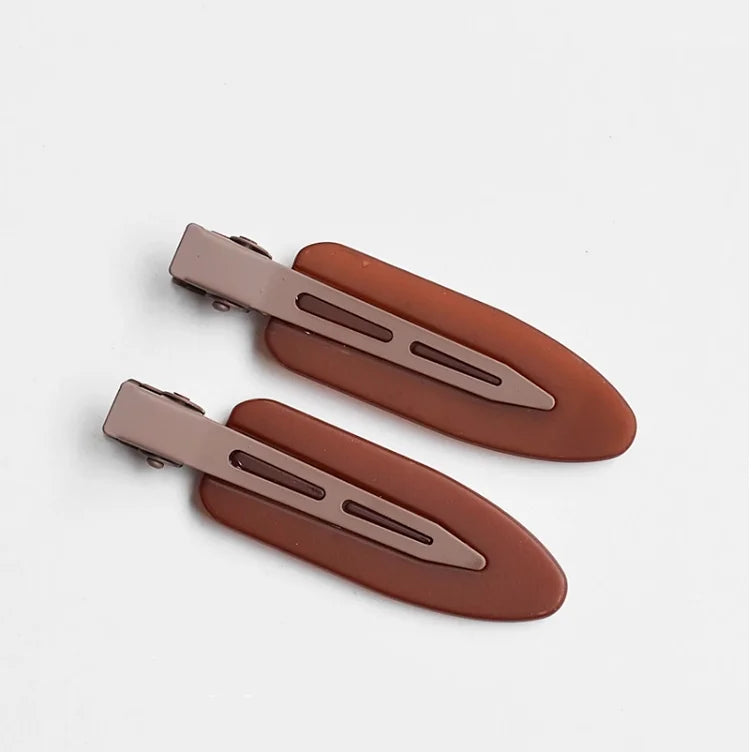 A set of two matte brown resin side hair clips lying on a white background.