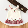 A white kids summer pinafore dress with strawberry and bunny print, featuring red trim and a plaid skirt.