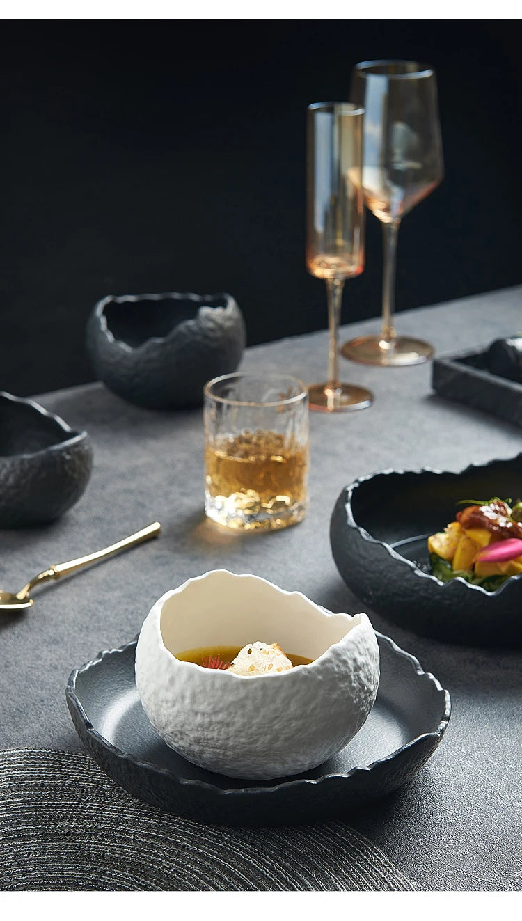 Nærbilde av en elegant hvit keramikkbolle med gyllen væske, på mørk grå overflate med glass