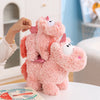 A pink unicorn plush toy with large eyes and pink accents is being held by a hand on a white surface.