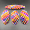 Tres juguetes antiestrés 3D de gusano con rayas coloridas sobre una superficie oscura.