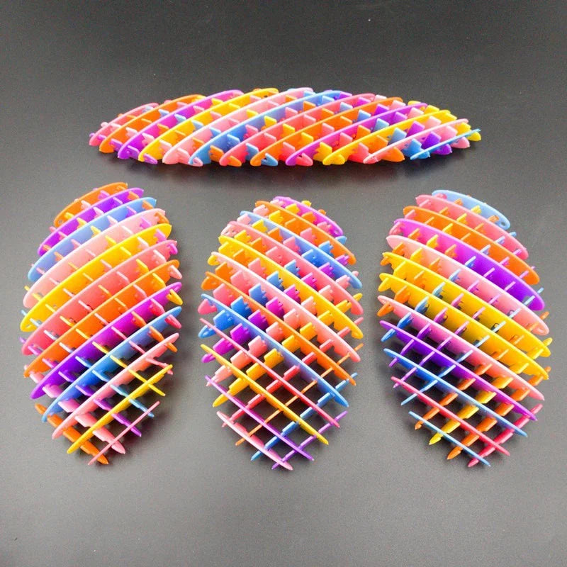 Tres juguetes antiestrés 3D de gusano con rayas coloridas sobre una superficie oscura.