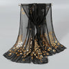 Black sheer chiffon scarf with gold shimmer detailing draped on a hanger.