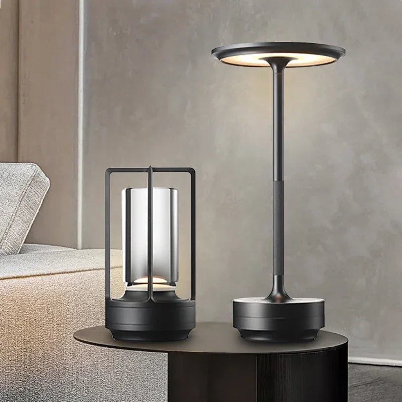 Lámpara de mesa LED negra moderna con pantalla circular y soporte alto sobre superficie oscura.
