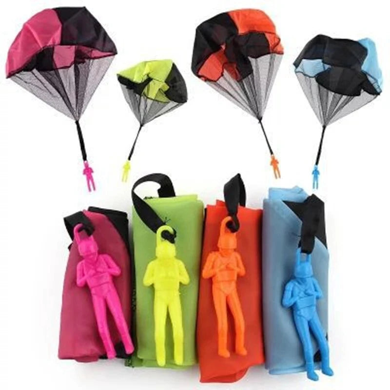 Juguetes paracaídas lanzados a mano en varios colores: rosa, negro, naranja y azul.