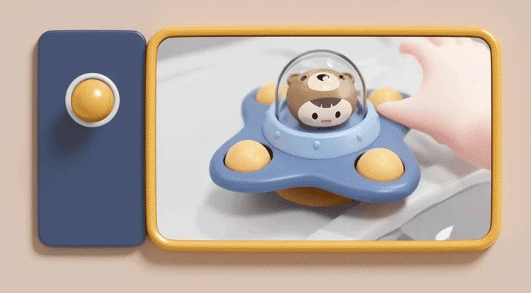 A close-up of a blue suction cup spinner bath toy with a bear head for toddlers is shown in a yellow frame.