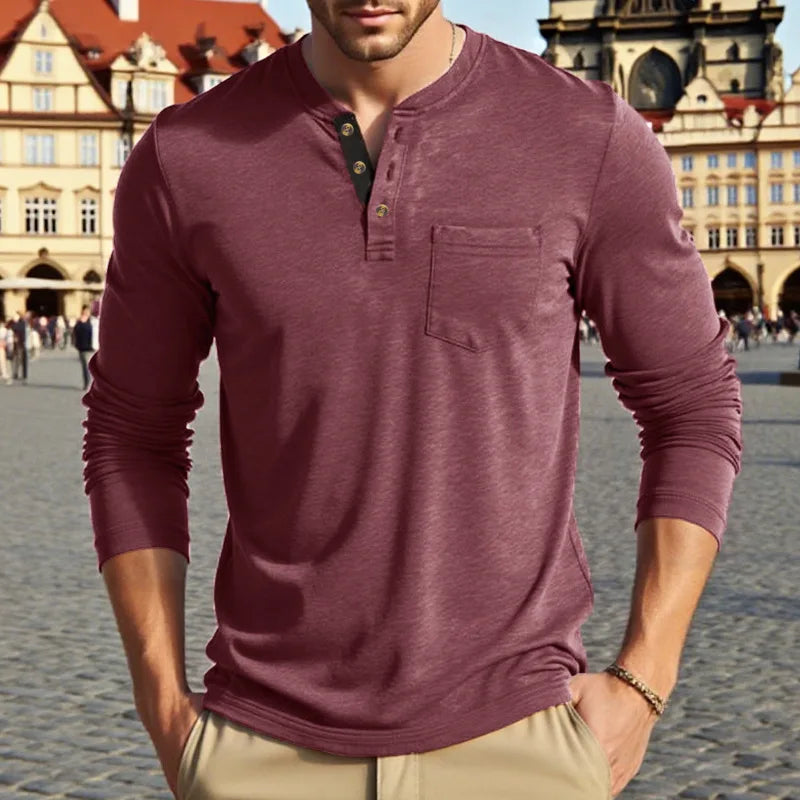 A man wearing a maroon long-sleeve casual shirt with a chest pocket, standing outdoors.