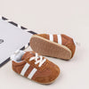 A pair of brown baby first walker shoes with white stripes and an anti-slip TPR sole resting on a white background.