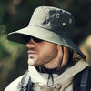 A man wearing a wide brim bucket hat and sunglasses outdoors.