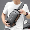 Hombre con camiseta blanca sostiene bolso negro antirrobo con puerto USB.